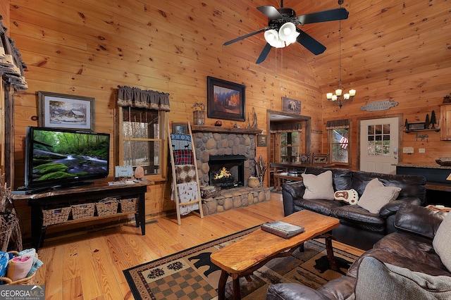 living area with high vaulted ceiling, light wood-style flooring, ceiling fan with notable chandelier, wood walls, and a fireplace