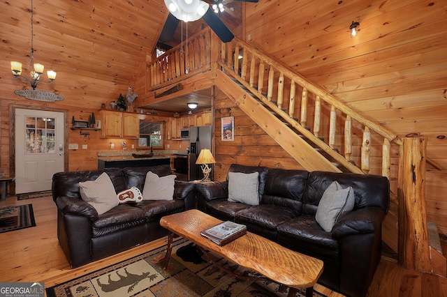 living room featuring light wood-type flooring, stairway, wooden ceiling, and wooden walls