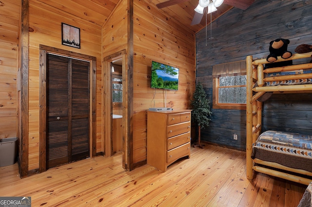 bedroom with wooden walls, wooden ceiling, light wood-style flooring, vaulted ceiling, and a closet