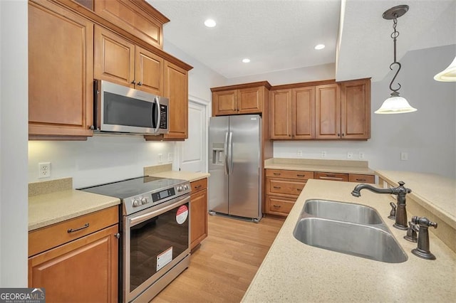 kitchen with light wood-style flooring, brown cabinets, stainless steel appliances, light countertops, and a sink