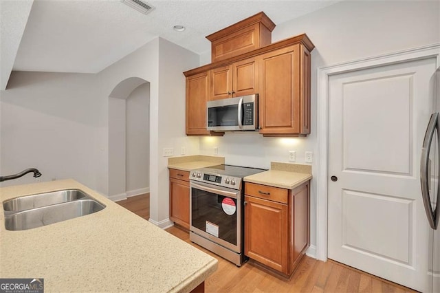 kitchen with light countertops, visible vents, appliances with stainless steel finishes, brown cabinetry, and a sink