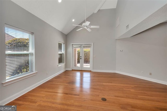 empty room featuring french doors, ceiling fan, wood finished floors, high vaulted ceiling, and baseboards