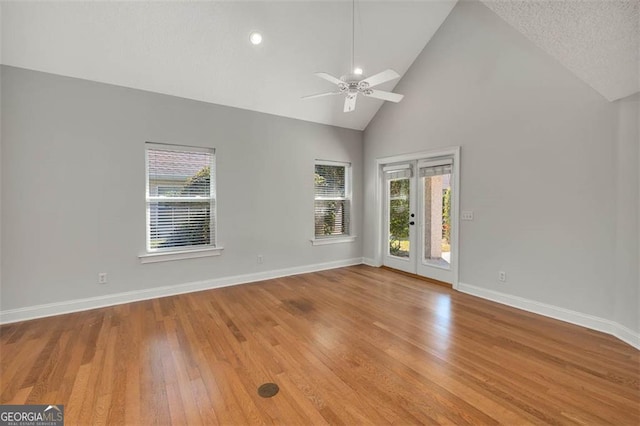 unfurnished living room with light wood-style floors, a ceiling fan, baseboards, and high vaulted ceiling