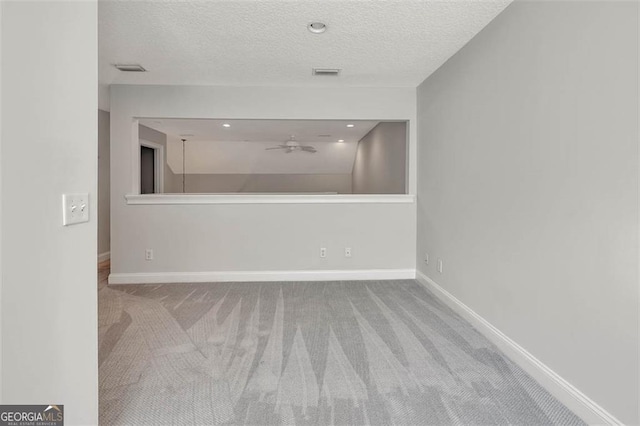 carpeted empty room featuring a textured ceiling, ceiling fan, visible vents, and baseboards