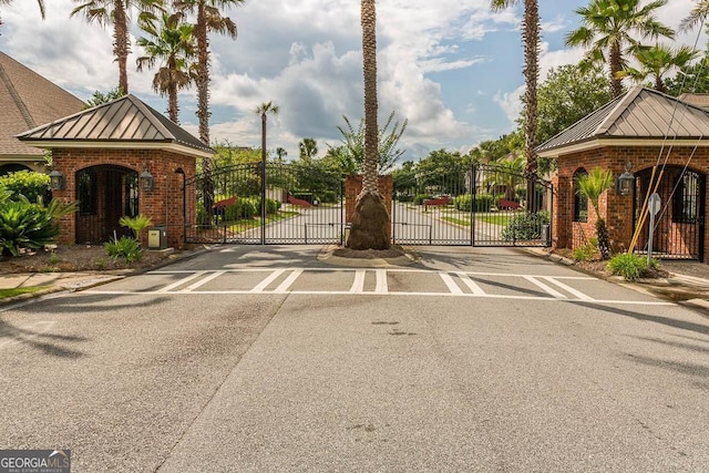 view of street featuring a gate, a gated entry, and curbs