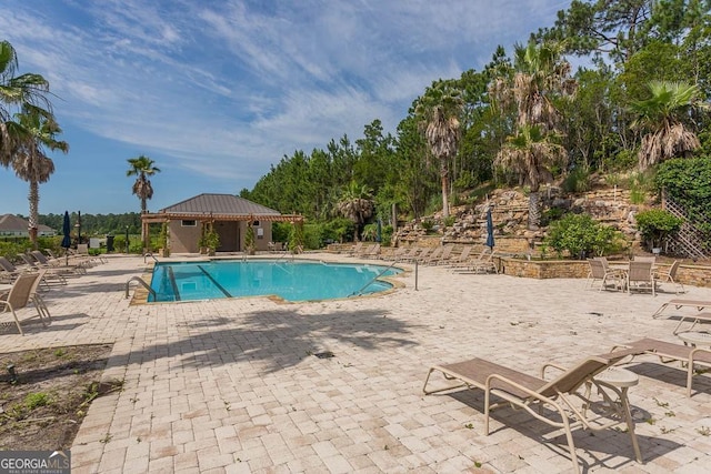 pool featuring a patio area, fence, and an outdoor structure