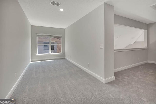 carpeted empty room with baseboards, visible vents, a textured ceiling, and recessed lighting