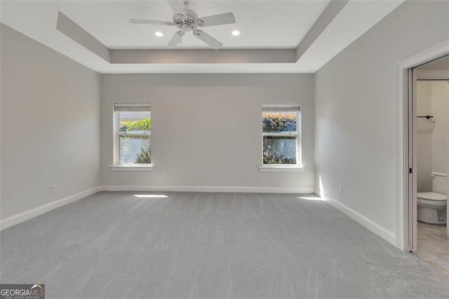 unfurnished bedroom featuring carpet, baseboards, a raised ceiling, and recessed lighting