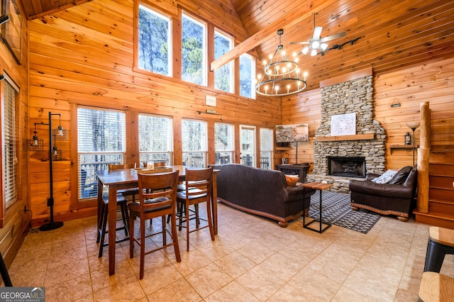 dining area featuring wooden ceiling, an inviting chandelier, wooden walls, and a stone fireplace