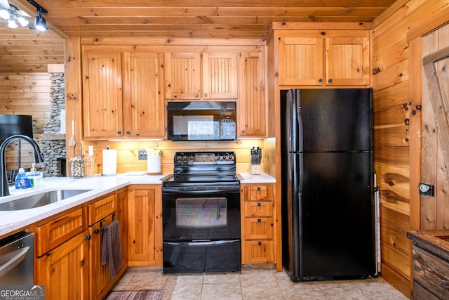 kitchen featuring light countertops, a sink, wood walls, and black appliances