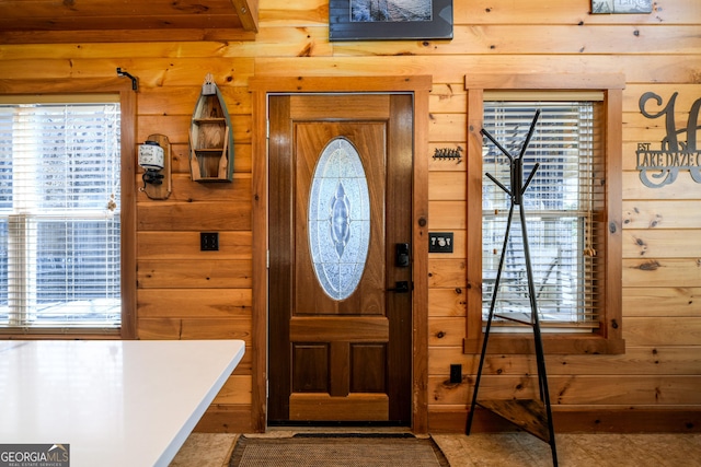 entryway with a wealth of natural light and wood walls