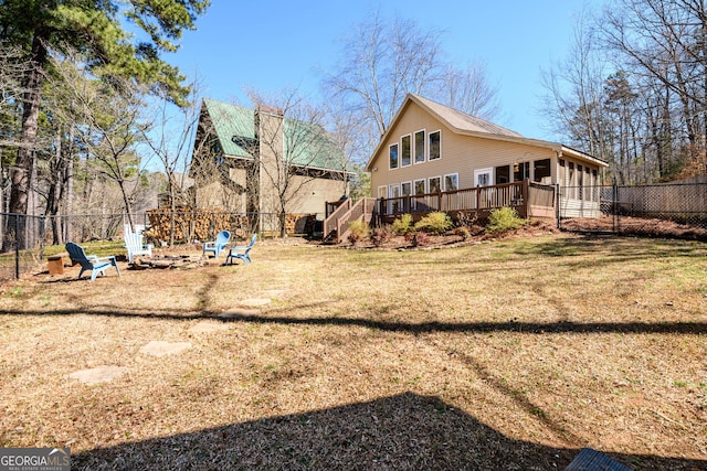 back of property featuring a deck, a yard, an outdoor fire pit, and a fenced backyard