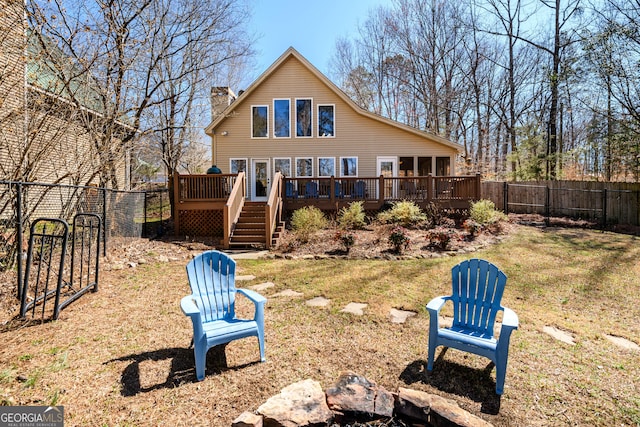 rear view of property featuring a fenced backyard, a chimney, a deck, and a yard