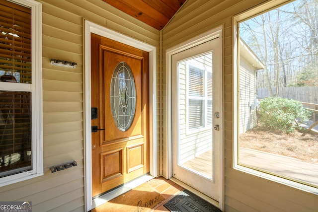 doorway to property with a porch and fence