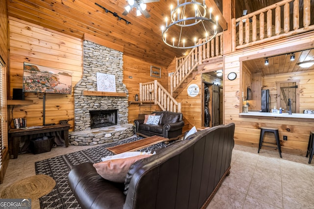 living room featuring wooden ceiling, wooden walls, a fireplace, a towering ceiling, and stairway