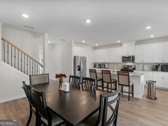 dining space with light wood-style flooring, recessed lighting, visible vents, baseboards, and stairway