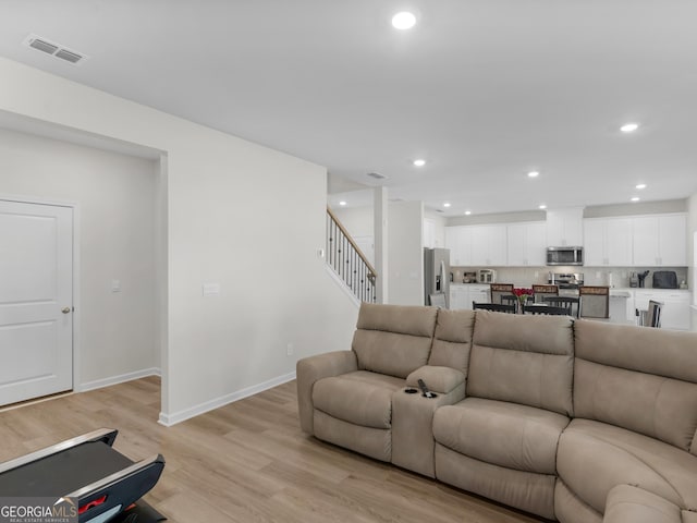 living area featuring visible vents, stairs, light wood-style flooring, and recessed lighting