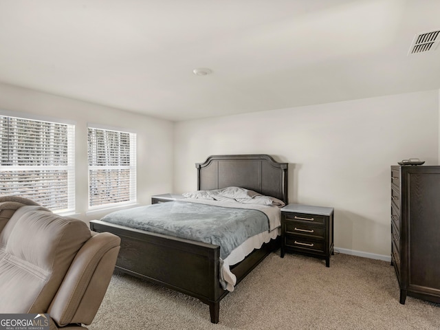 bedroom with baseboards, visible vents, and light colored carpet