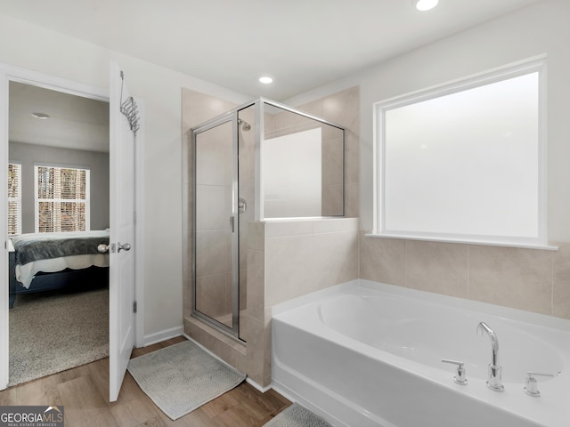 ensuite bathroom featuring connected bathroom, recessed lighting, wood finished floors, a bath, and a stall shower