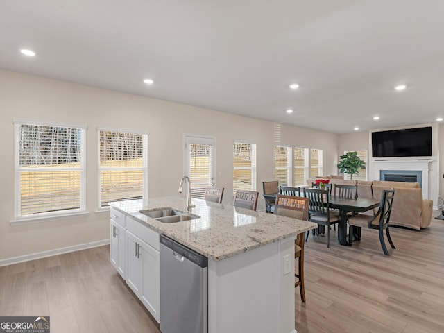 kitchen with a sink, a fireplace, white cabinetry, stainless steel dishwasher, and recessed lighting