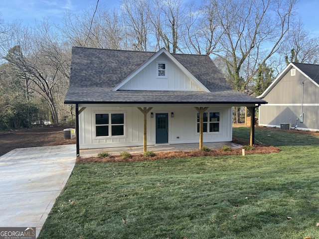 view of front facade with roof with shingles, central air condition unit, a porch, board and batten siding, and a front yard