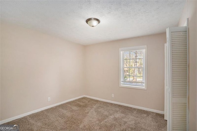 unfurnished bedroom with a textured ceiling, carpet floors, and baseboards