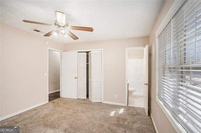 unfurnished bedroom featuring baseboards, a ceiling fan, ensuite bathroom, carpet flooring, and a closet