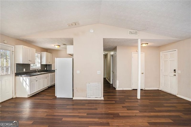 kitchen with lofted ceiling, visible vents, and freestanding refrigerator