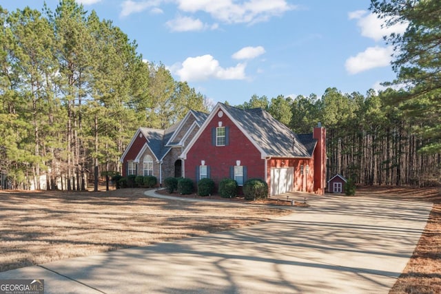 view of front of home featuring an outbuilding, concrete driveway, a chimney, and an attached garage