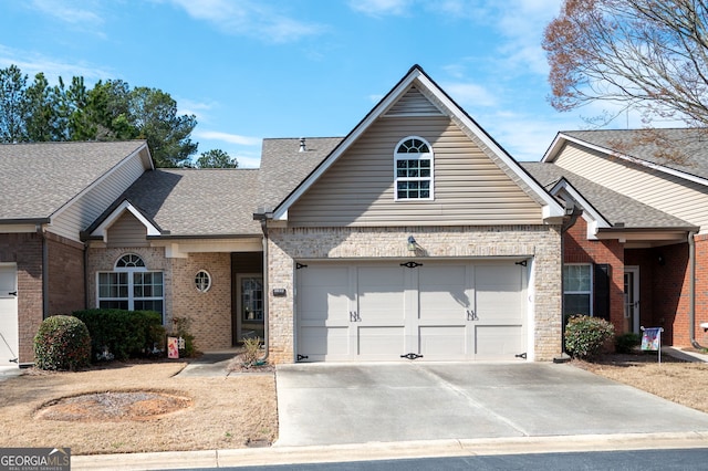 view of front of home featuring concrete driveway, an attached garage, brick siding, and a shingled roof