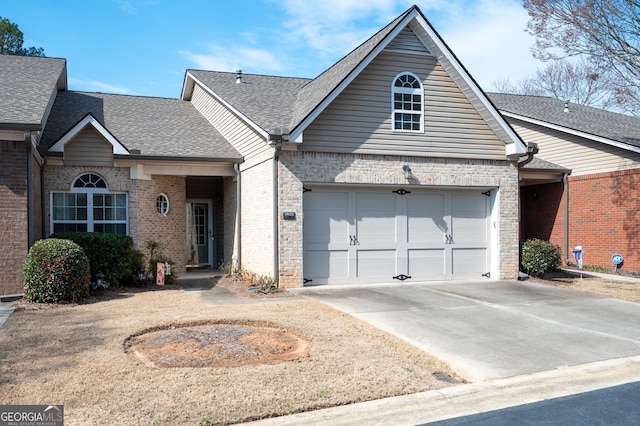 view of front of house featuring concrete driveway, brick siding, and a shingled roof