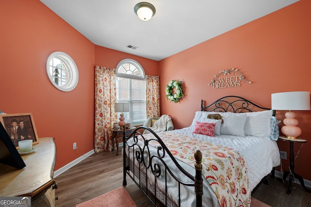 bedroom featuring visible vents, baseboards, and wood finished floors