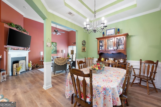 dining room featuring ceiling fan with notable chandelier, a tray ceiling, wood finished floors, and visible vents