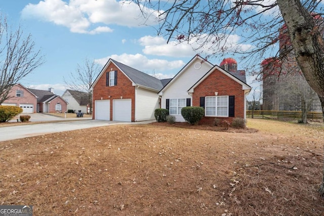 traditional home with brick siding, a chimney, concrete driveway, an attached garage, and fence