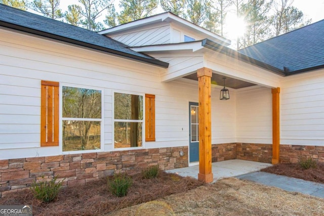 property entrance with stone siding and a shingled roof