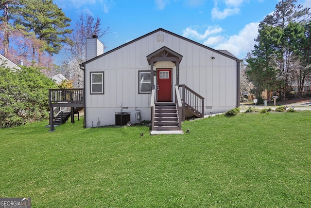 view of front of home featuring a front yard, a chimney, and central AC unit