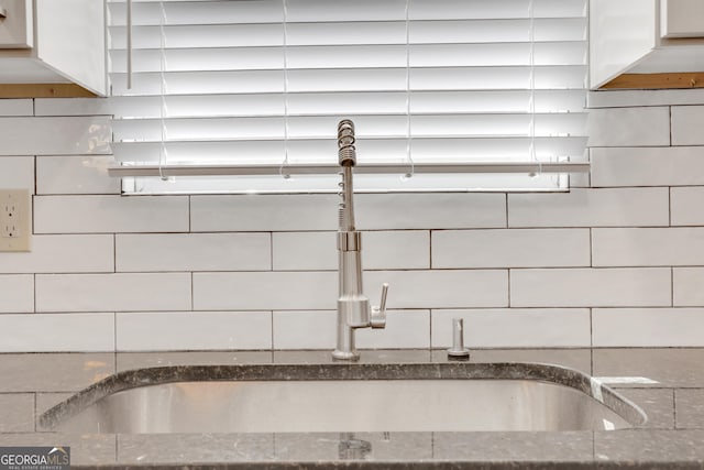 interior details with white cabinetry, dark stone counters, and a sink