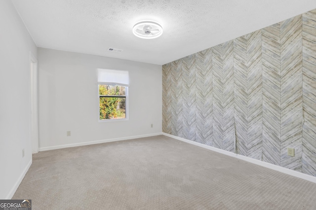 spare room featuring a textured ceiling, carpet floors, and baseboards