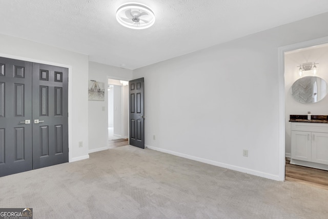 unfurnished bedroom with a textured ceiling, a closet, carpet, and baseboards