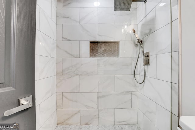 bathroom featuring a tile shower and toilet