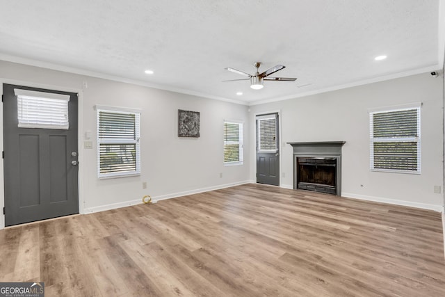 unfurnished living room with light wood-style flooring, a fireplace, baseboards, and crown molding