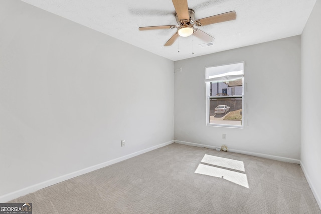 spare room featuring carpet floors, visible vents, ceiling fan, a textured ceiling, and baseboards