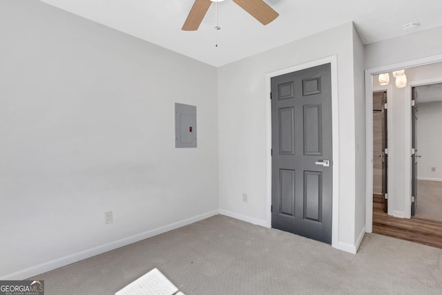 unfurnished bedroom with carpet floors, ceiling fan, electric panel, and baseboards