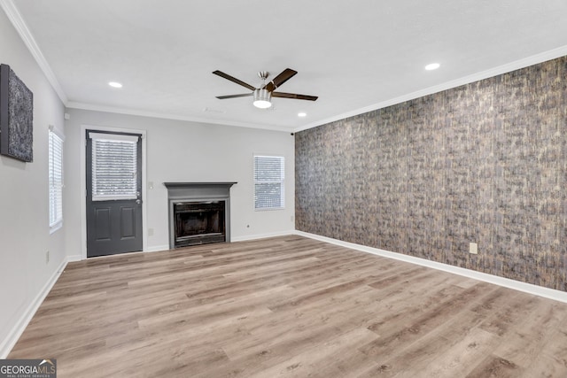 unfurnished living room featuring a wealth of natural light, ornamental molding, and wood finished floors