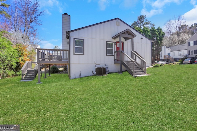 back of house featuring central air condition unit, a chimney, a deck, and a lawn