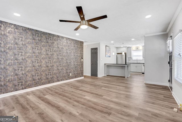 unfurnished living room with baseboards, light wood-style floors, and crown molding