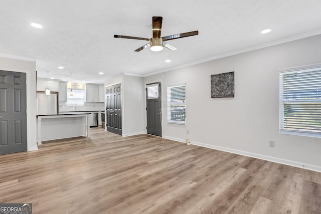 unfurnished living room with light wood finished floors, ornamental molding, recessed lighting, and baseboards