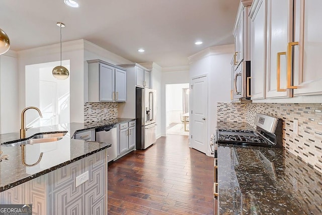 kitchen with stainless steel appliances, dark wood-style flooring, a sink, ornamental molding, and dark stone countertops