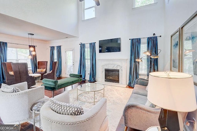 living room with a fireplace, wood finished floors, and a towering ceiling