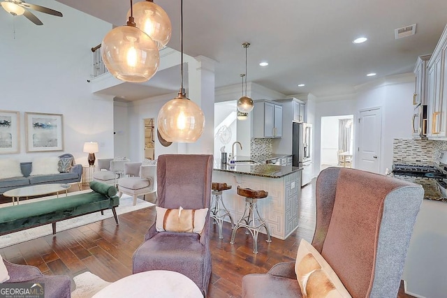 living room featuring a ceiling fan, visible vents, dark wood-type flooring, and recessed lighting